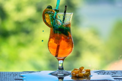 清楚酒杯与橙色液体和蓝草
